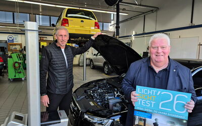 Fritz Faupel und Kai Bremmer stehen mit einem Auto und Prüfgerät in der Kfz-Werkstatt beim Licht-Sicht-Test.